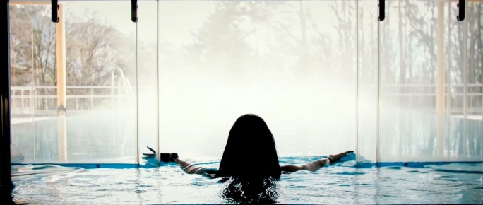 Frau schwimmt durch automatische Glas-Schiebetür in den Poolaussenbereich | Svoboda Edelstahlpools