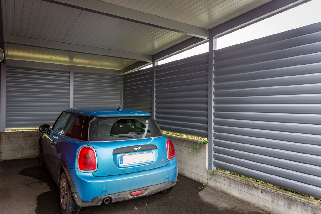 Carport 17 b | Unteransicht Carport mit seitlichem grauem Sichtschutz aus Alu-Lamellen mit blauem Auto | Svoboda Metalltechnik