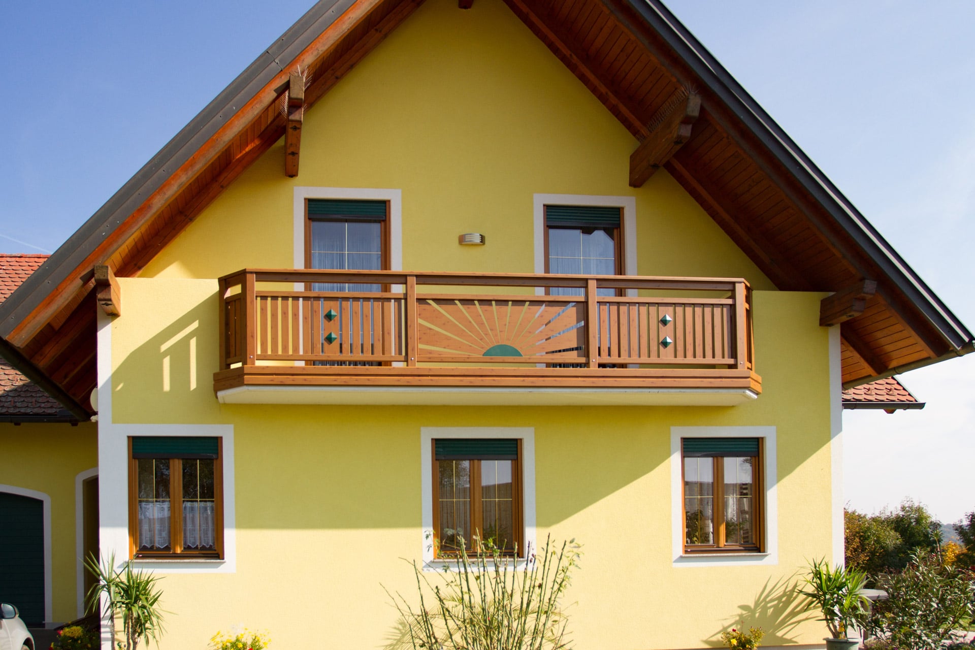 Amstetten 10 H a | klassicher Balkon mit Dekorsonne und senkrechten Latten bei gelbem Haus | Svoboda