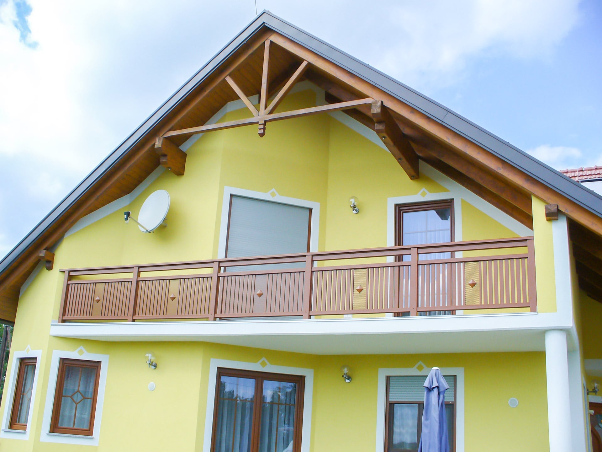 Krieglach 13 a | Aluminium Balkon braun mit Lochblech & Knopf bei Haus gelb mit Spitzdach | Svoboda