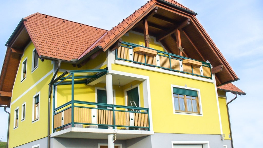 Krieglach 21 b | grün-brauner Alu Balkon bei gelbem Haus mit Krüppelwalmdach | Svoboda Metalltechnik